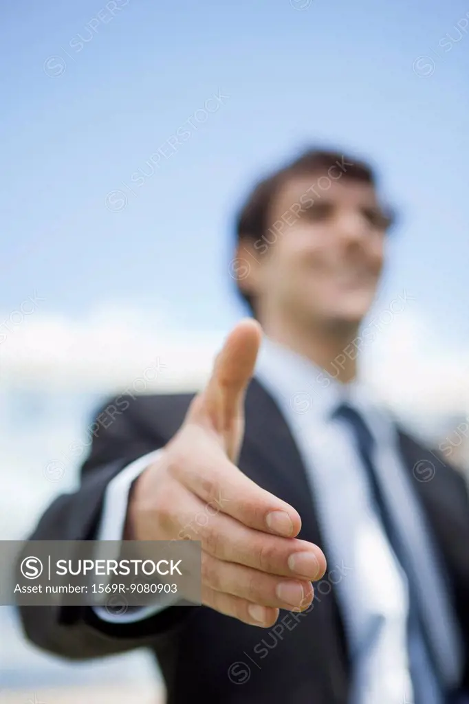 Businessman extending hand for handshake, low angle view