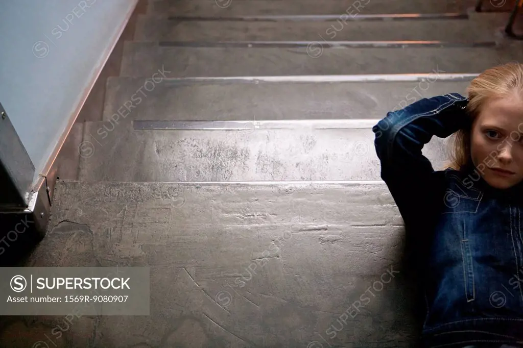 Young woman lying on stairs with hands behind head