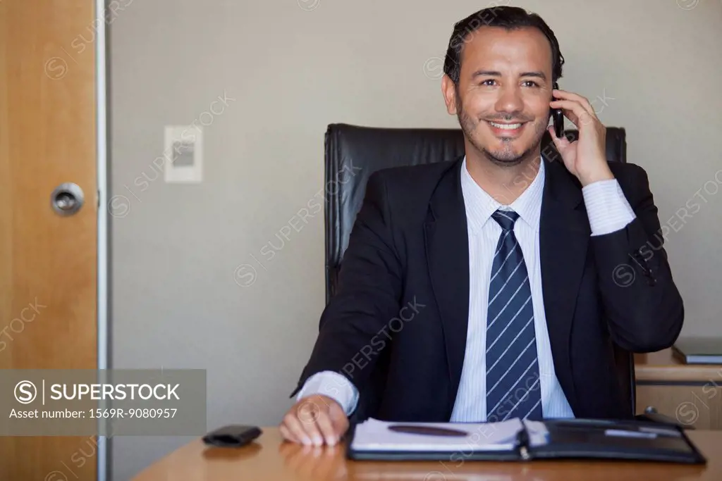 Mid-adult executive talking on cell phone in office