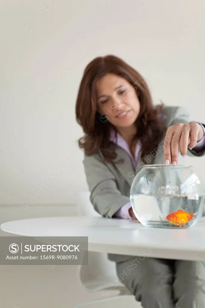Businesswoman feeding goldfish