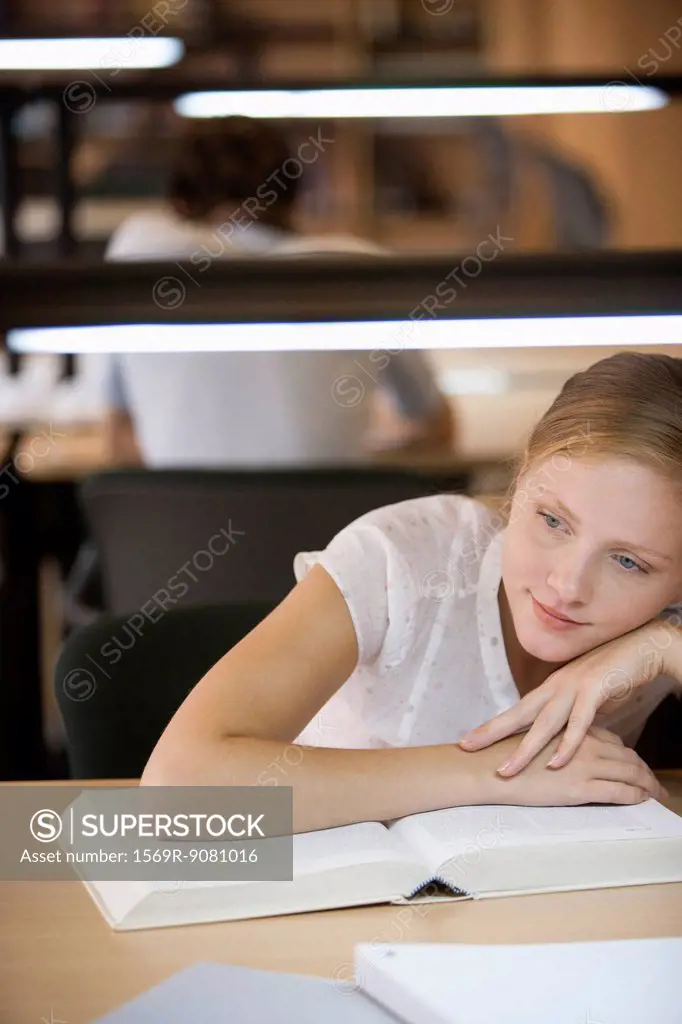 Young woman daydreaming while studying