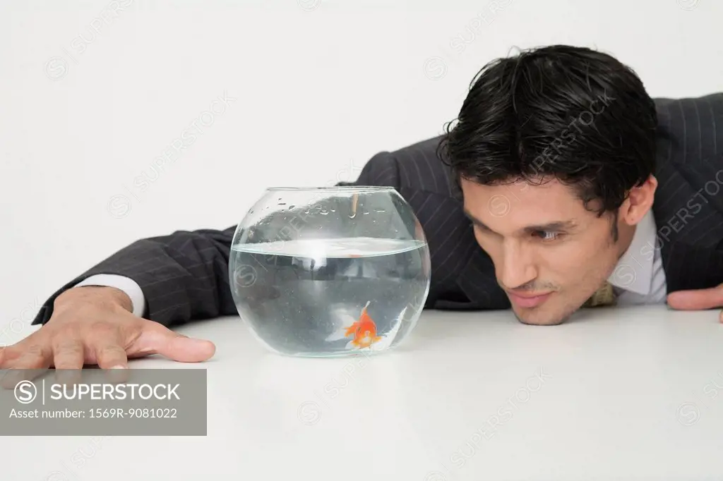 Businessman looking at goldfish in fishbowl