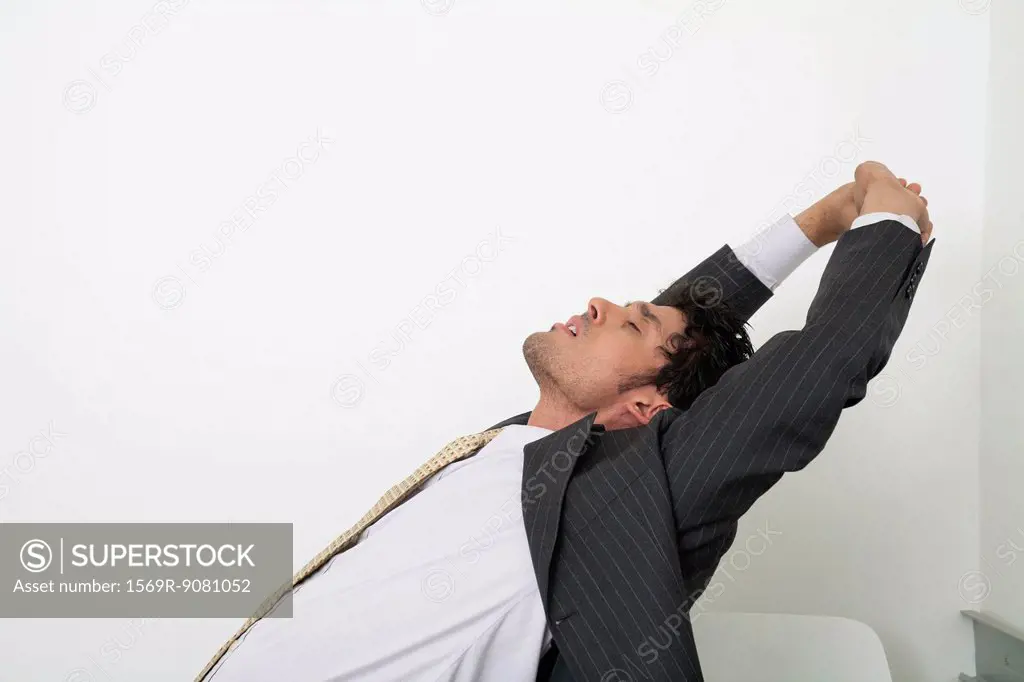 Exhausted mid-adult businessman stretching with eyes closed