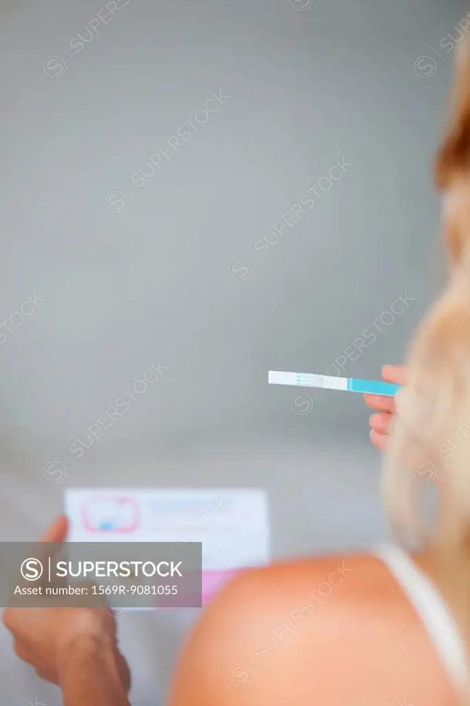 Woman holding pregnancy test, cropped