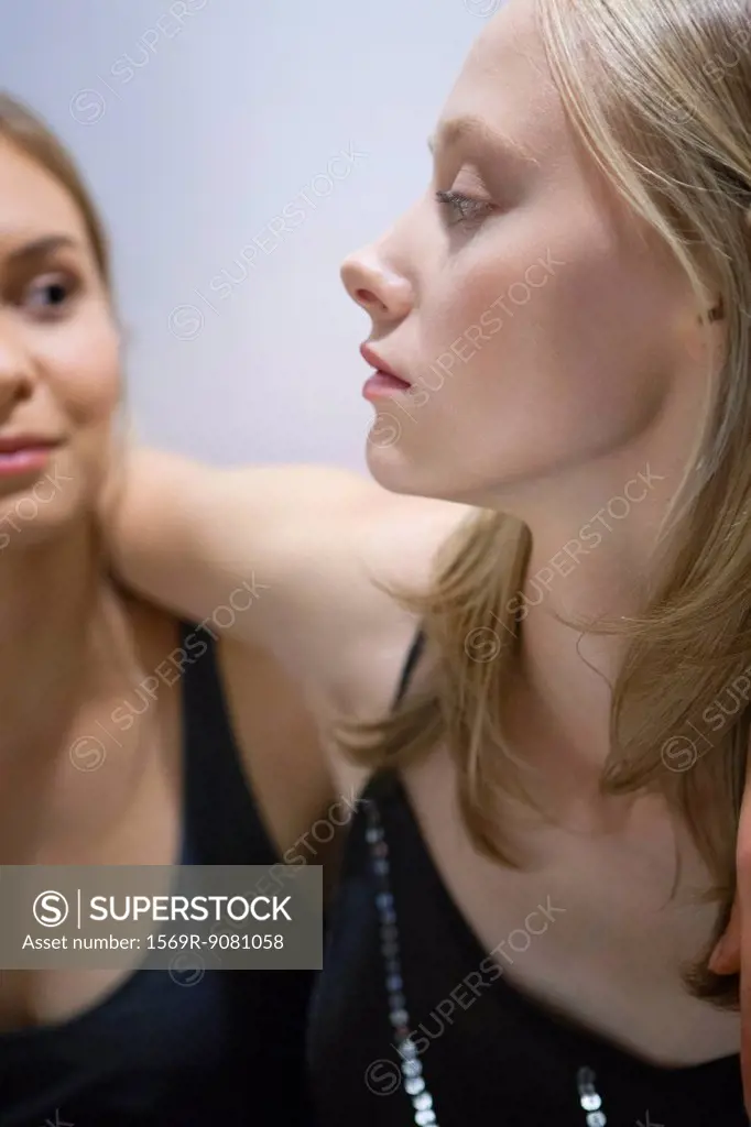 Young woman with arm around girlfriend's shoulder