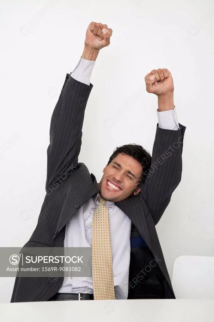 Mid-adult businessman raising arms in celebration