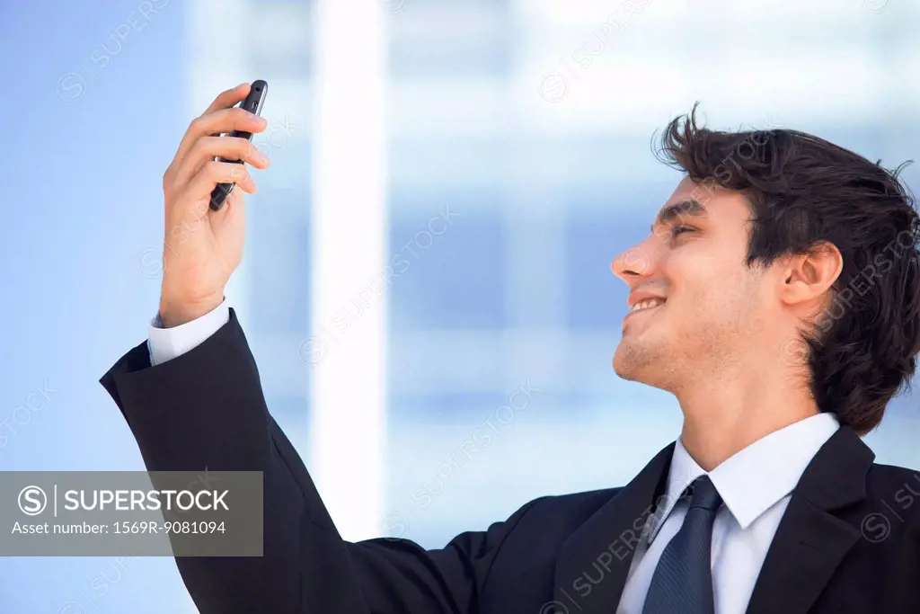 Young executive video calling on cell phone outdoors