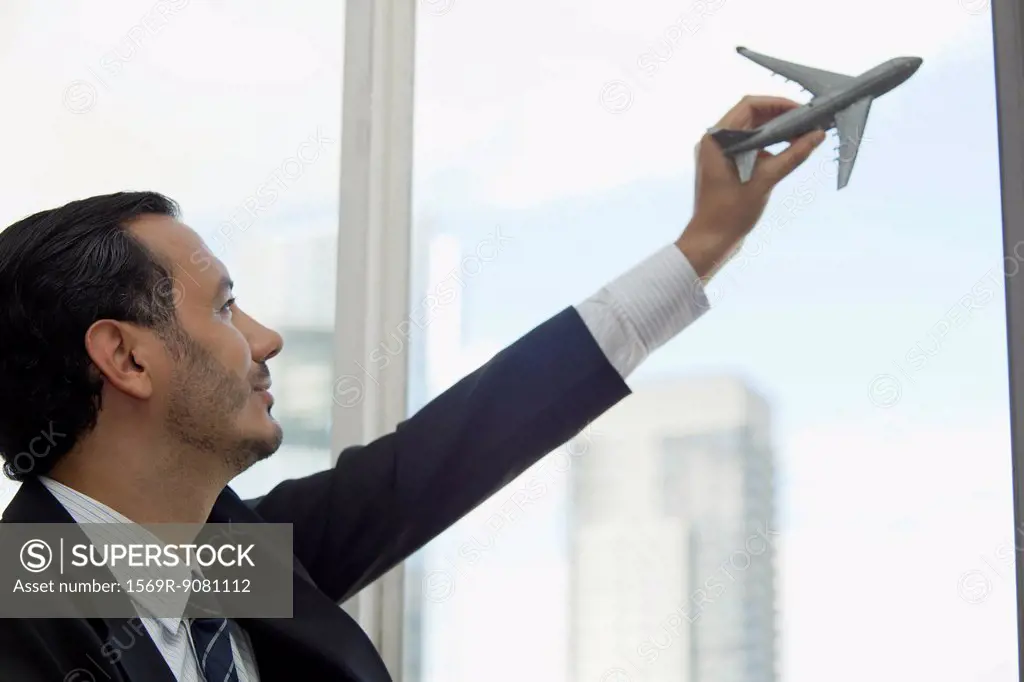 Mid-adult executive playing with toy airplane