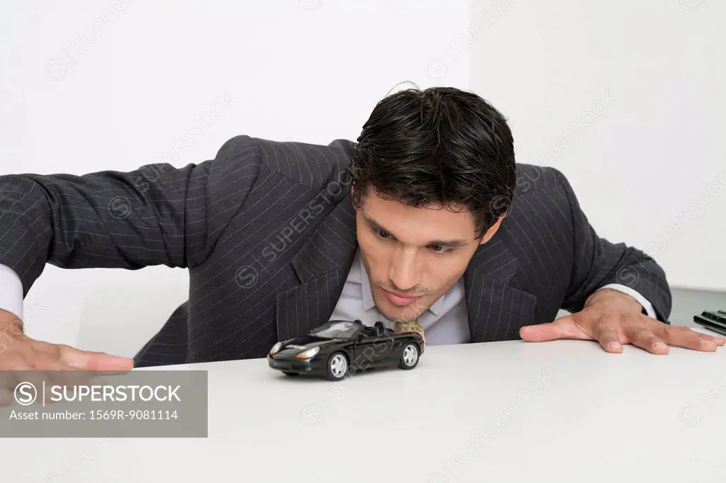Mid-adult businessman staring at toy car