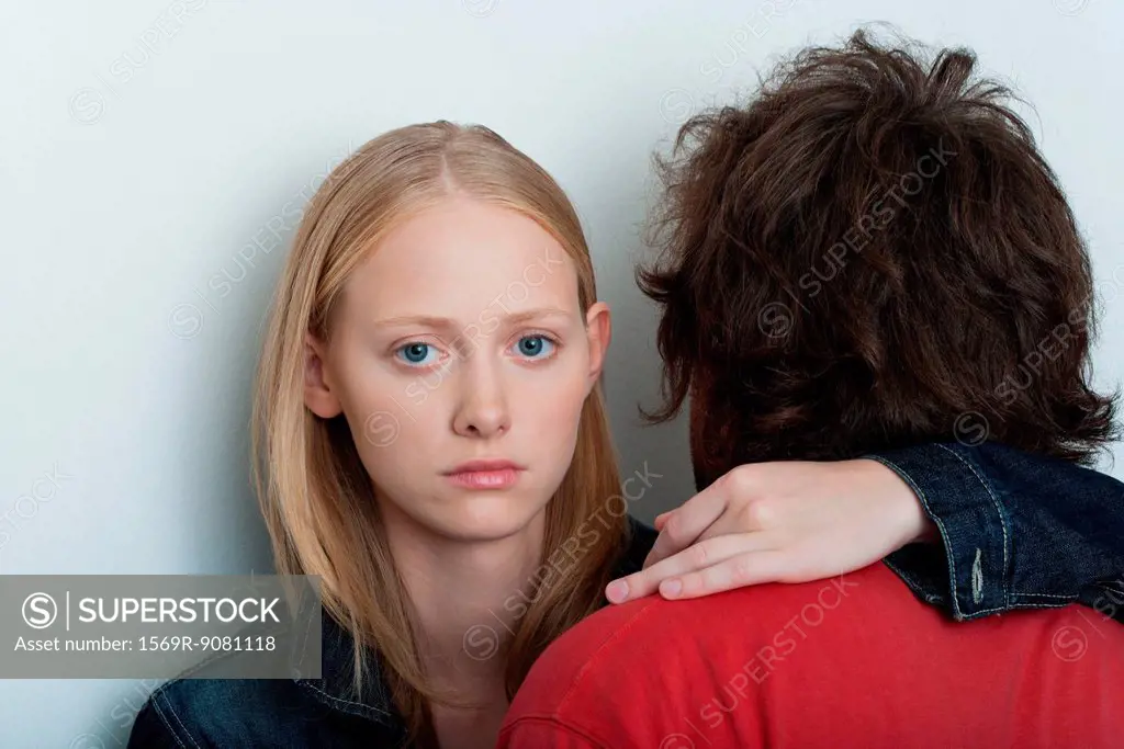 Young woman embracing man, looking at camera with serious expression
