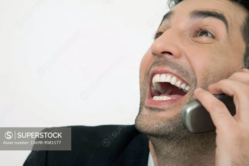 Mid-adult businessman laughing while talking on cell phone, cropped