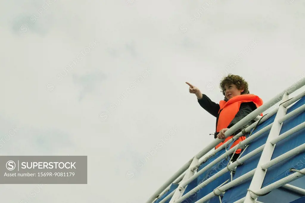 Boy watching the horizon, on the upper deck of a boat