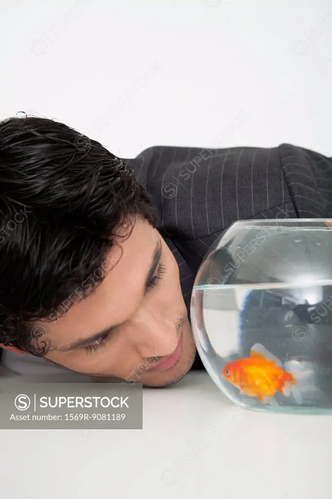 Businessman staring at goldfish in fishbowl