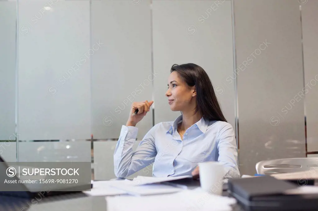 Businesswoman sitting at desk, looking away in thought