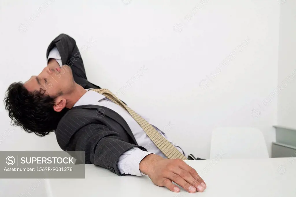 Exhausted mid-adult businessman leaning back on chair with eyes closed