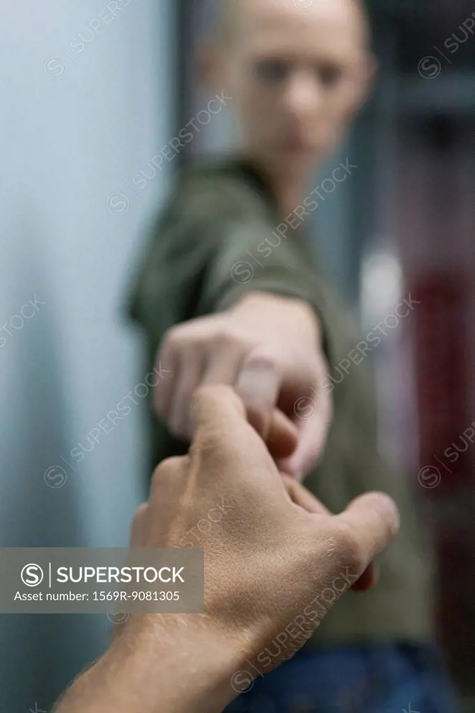 Man's hand reaching to hold woman's hand