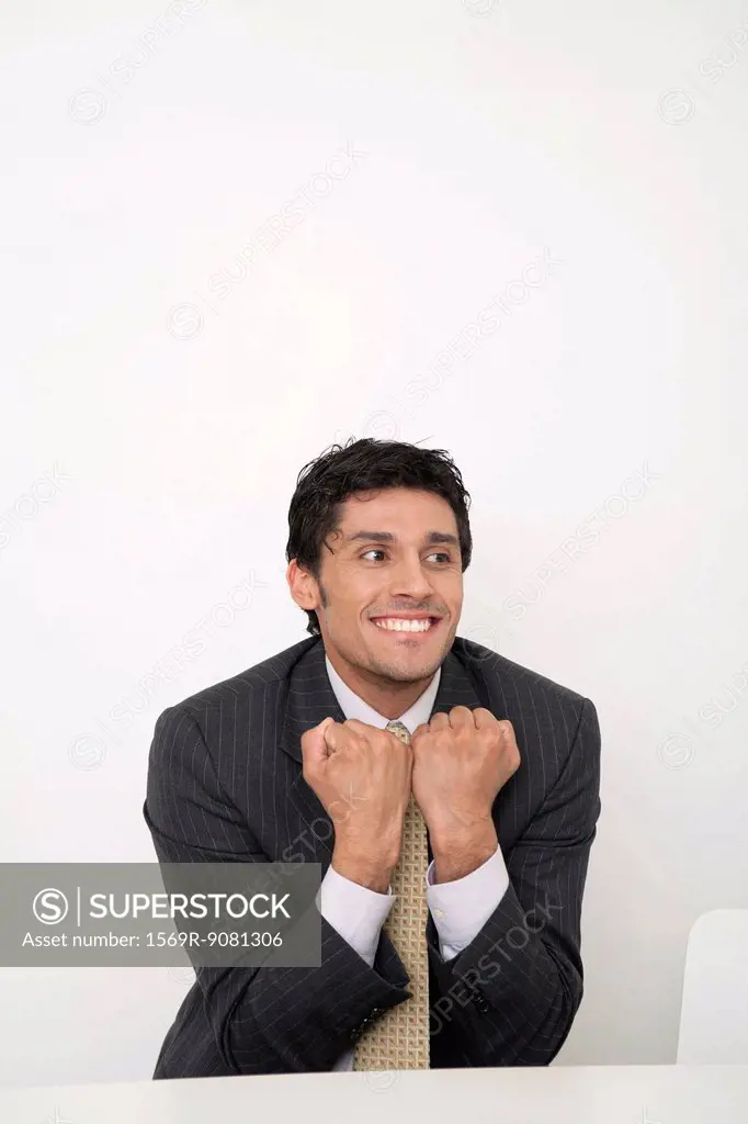 Mid-adult businessman clenching fists in front of chest, smiling