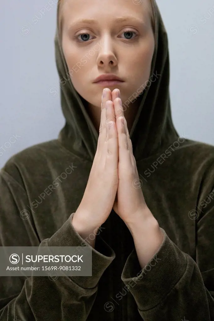Young woman with hands clasped in prayer, portrait