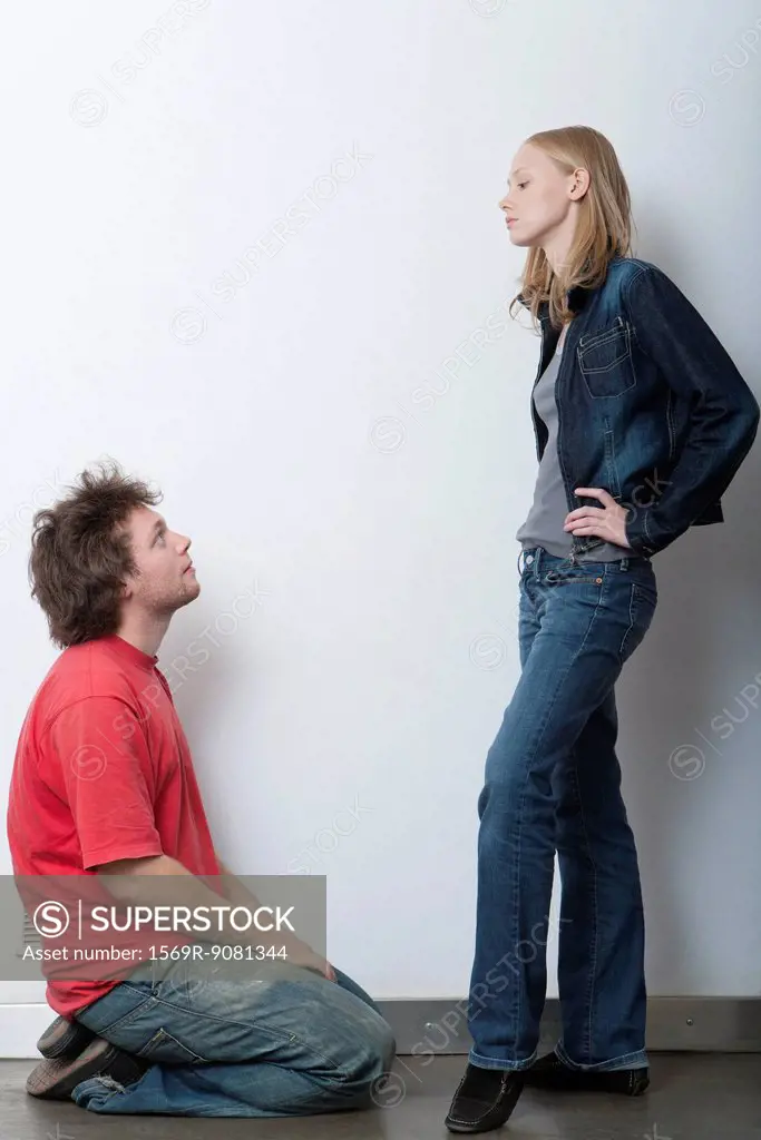 Young man kneeling in front of angry girlfriend