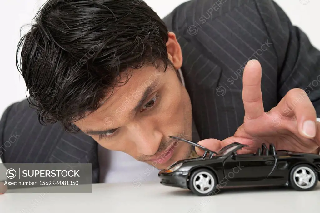 Mid-adult businessman looking at toy car