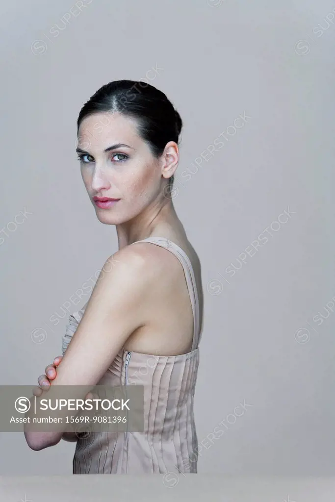 Woman with arms folded, looking over shoulder, portrait