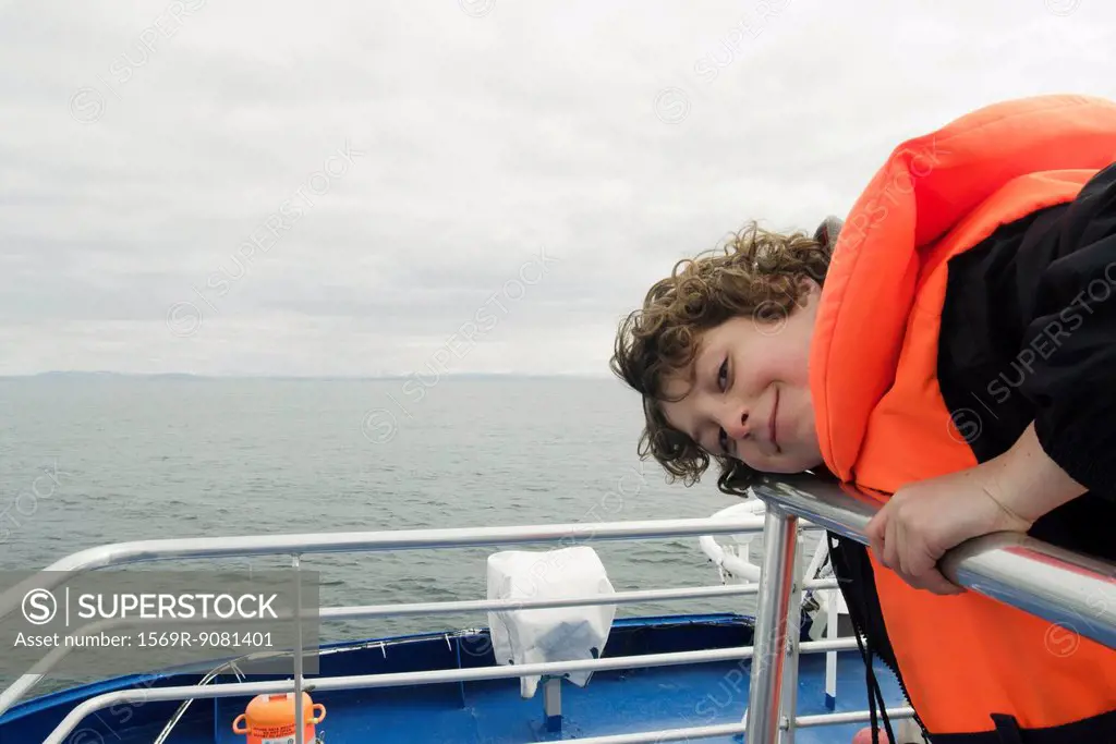 Boy leaning on the deck of a boat, smiling