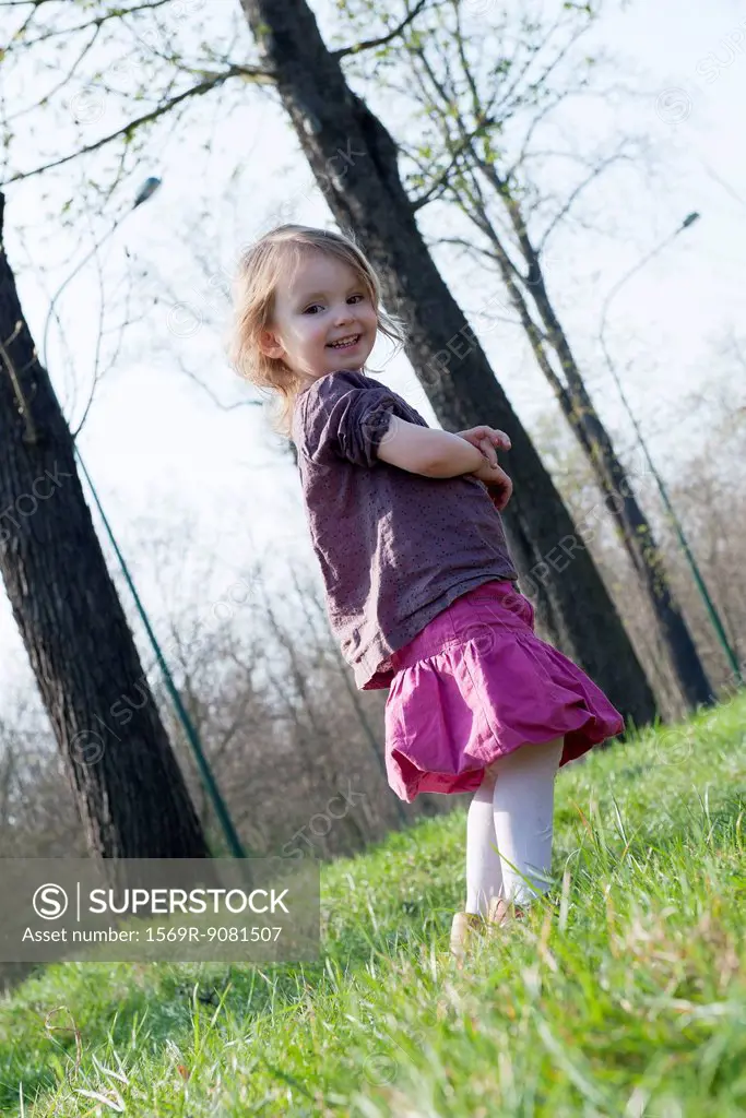 Little girl smiling outdoors, full length portrait
