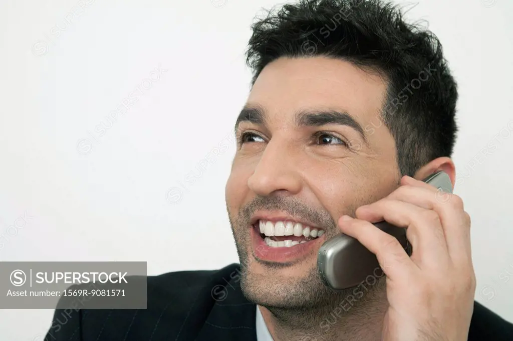 Mid-adult businessman talking on cell phone, smiling