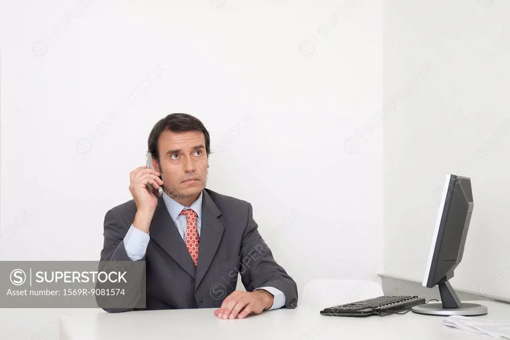 Mature businessman using cell phone at desk