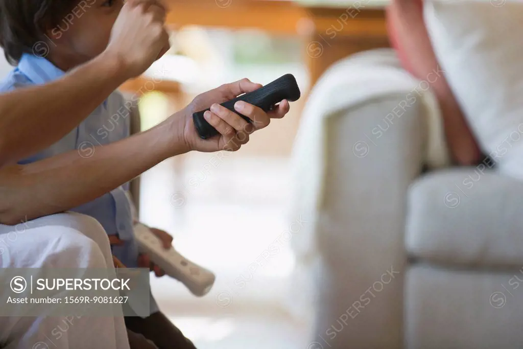 Man and child playing video game using remote controls, cropped