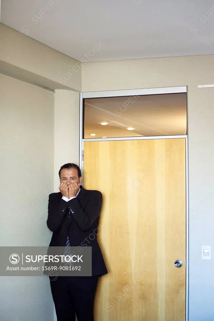 Businessman standing in corner with terrified expression