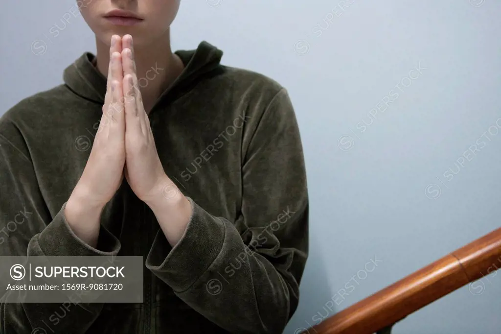 Young woman with hands clasped in prayer, cropped