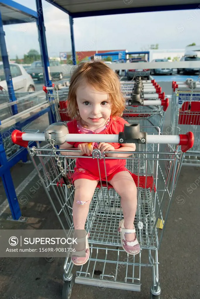 Little girl sitting in shopping cart