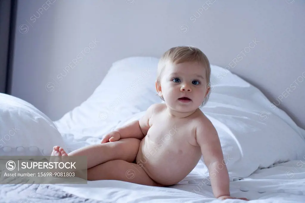 Naked baby reclining on bed, portrait