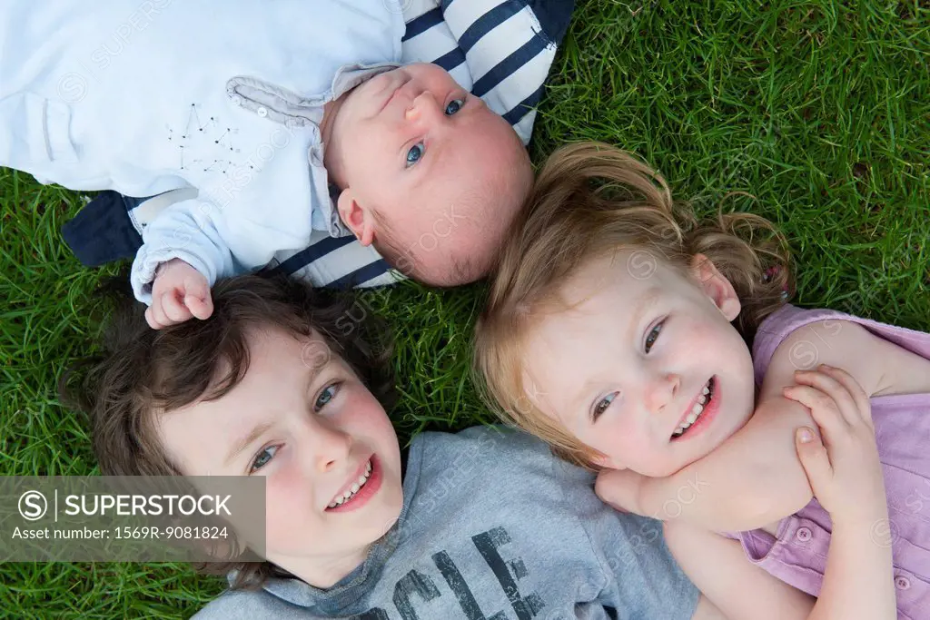 Young siblings lying on grass, portrait