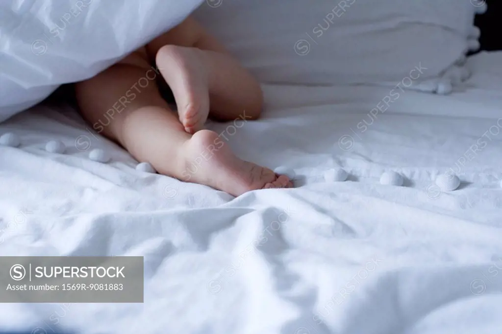 Baby crawling under duvet, cropped