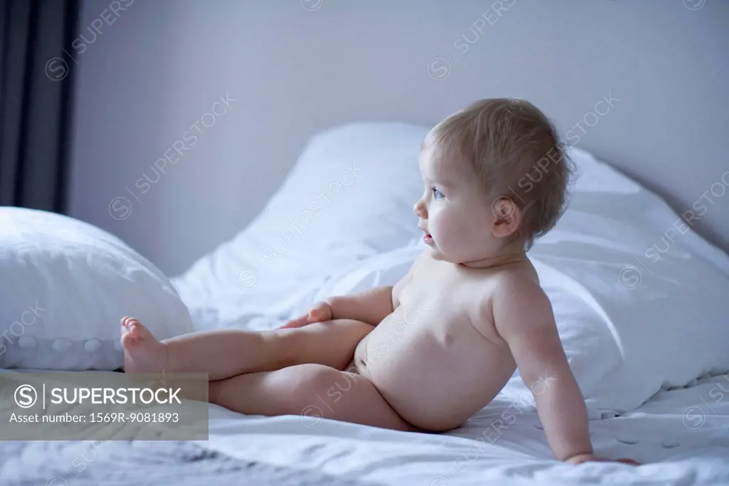Naked baby reclining on bed