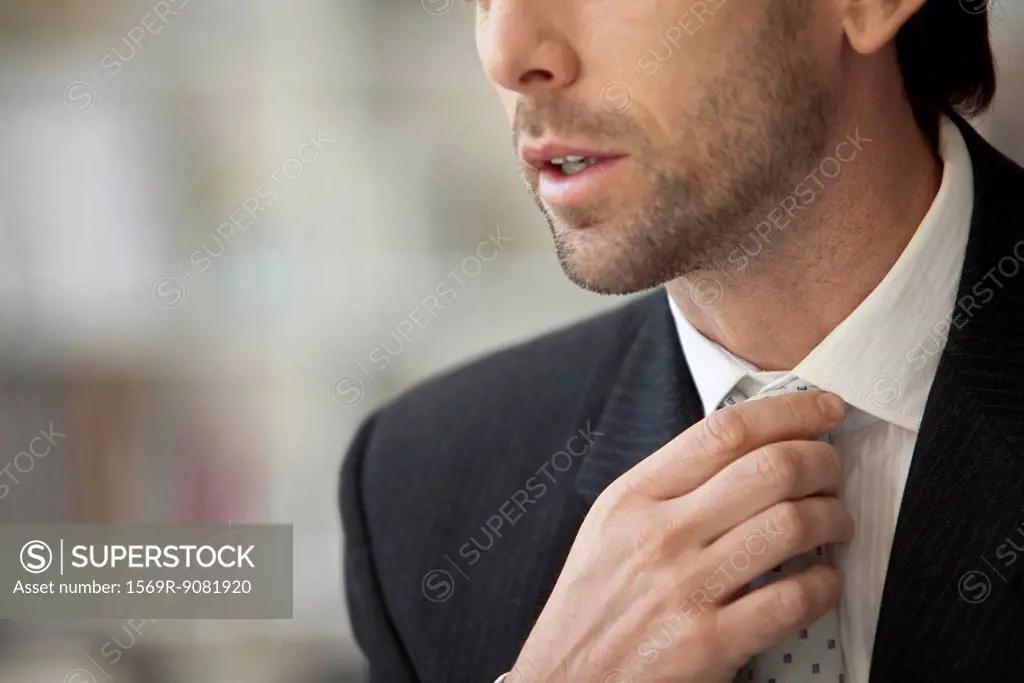 Businessman adjusting tie, cropped