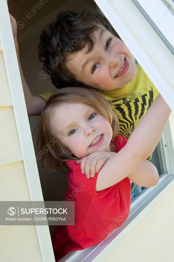 Young siblings looking out open window, portrait