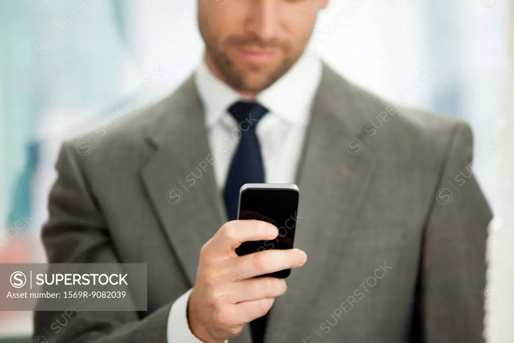 Businessman sending text message on cell phone, cropped