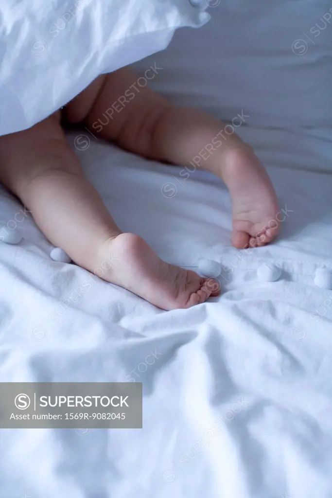 Baby's barefeet under duvet, cropped