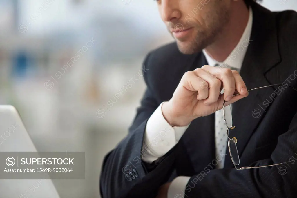 Businessman sitting with glasses in hand, cropped