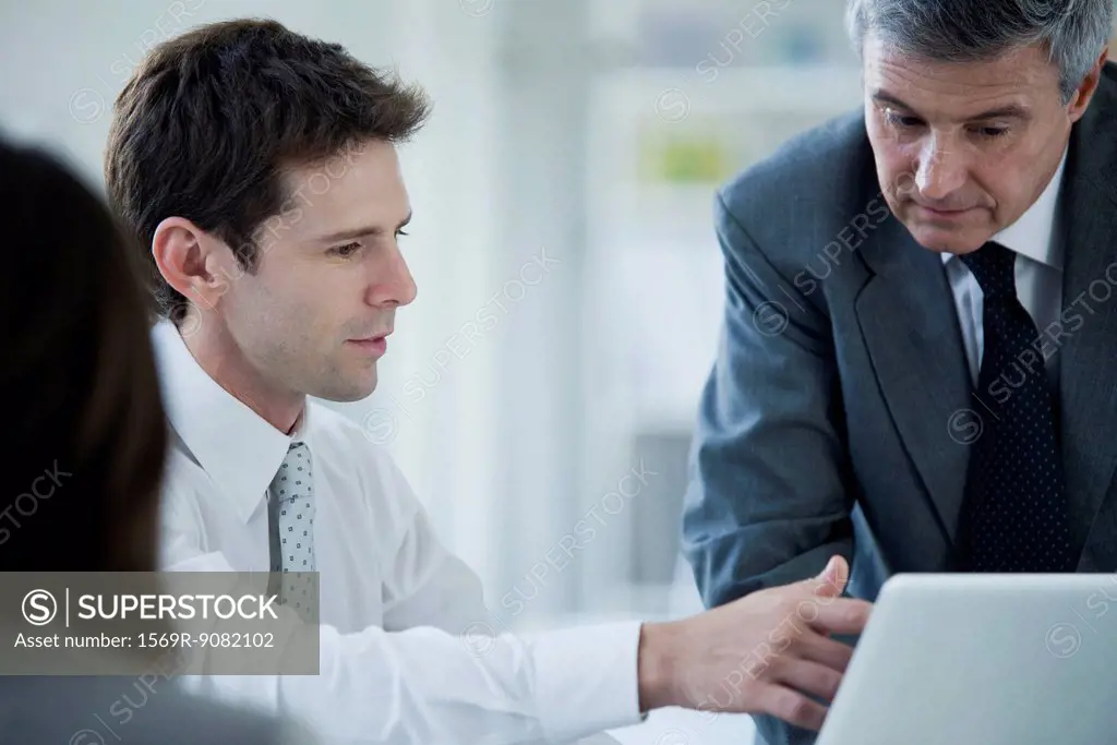 Business associates collaborating with laptop computer
