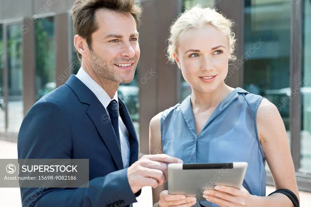 Real estate agent with digital tablet showing property to potential buyer