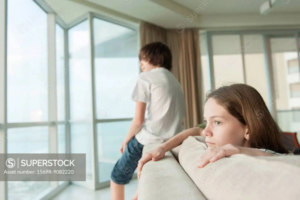 Siblings sitting on sofa, looking out window
