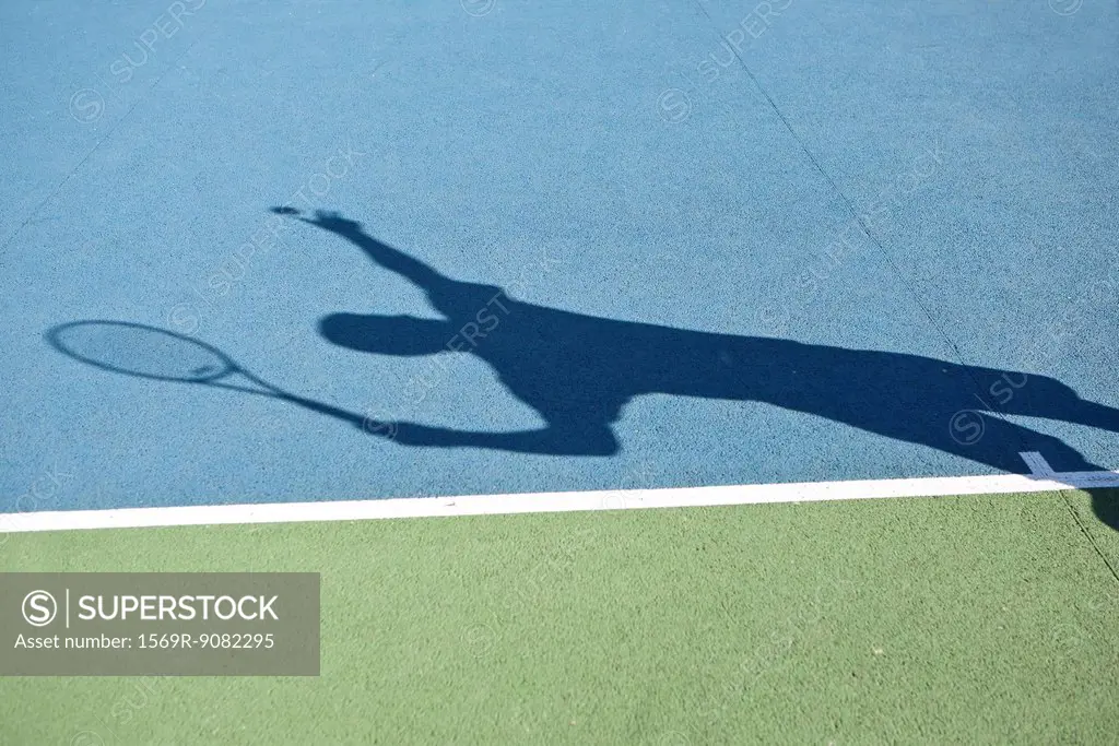 Shadow of tennis player serving ball