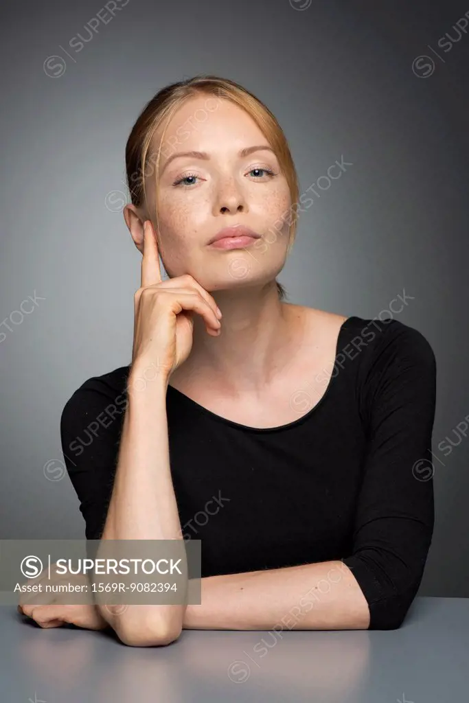 Young woman sitting with hand under chin, portrait