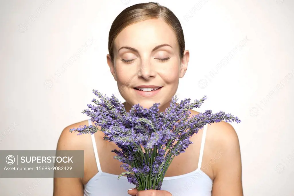 Woman smelling bouquet of fresh lavender with eyes closed
