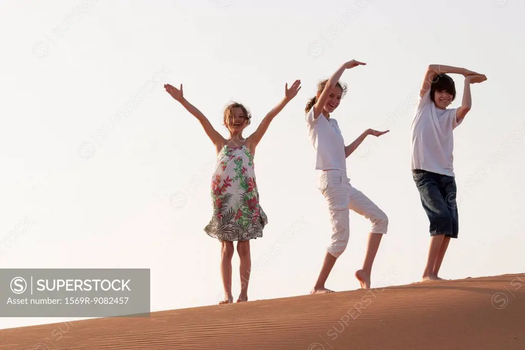Children walking in desert, making gestures with arms