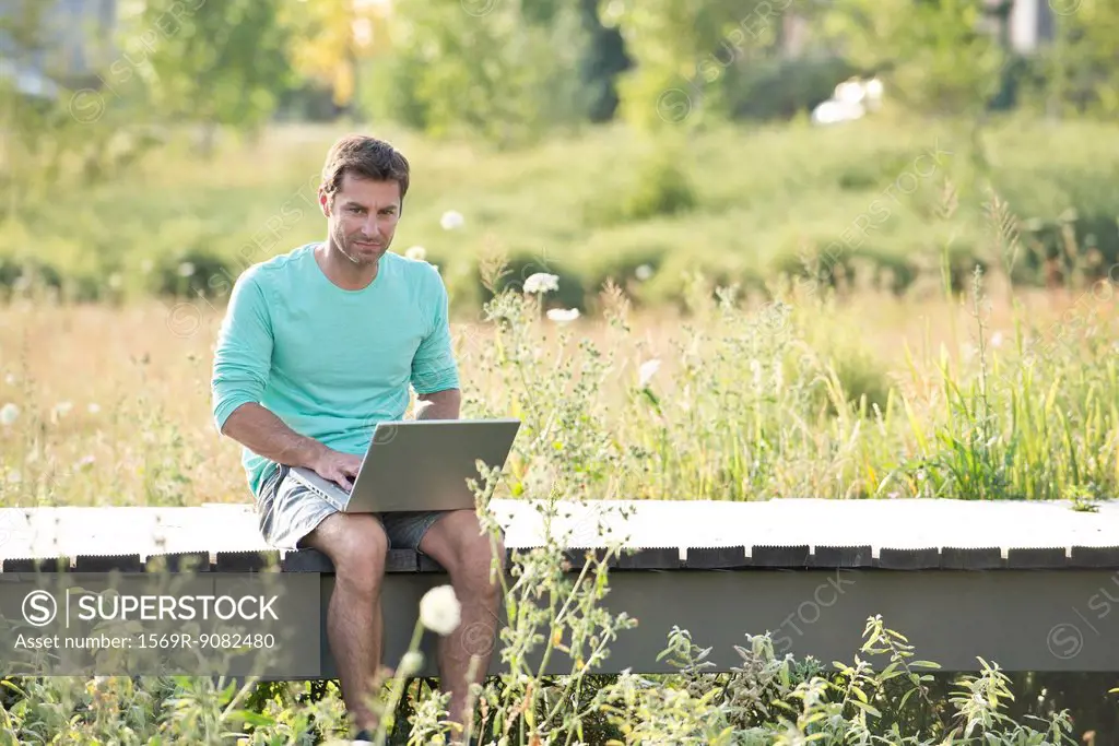 Man using laptop computer while sitting out in nature